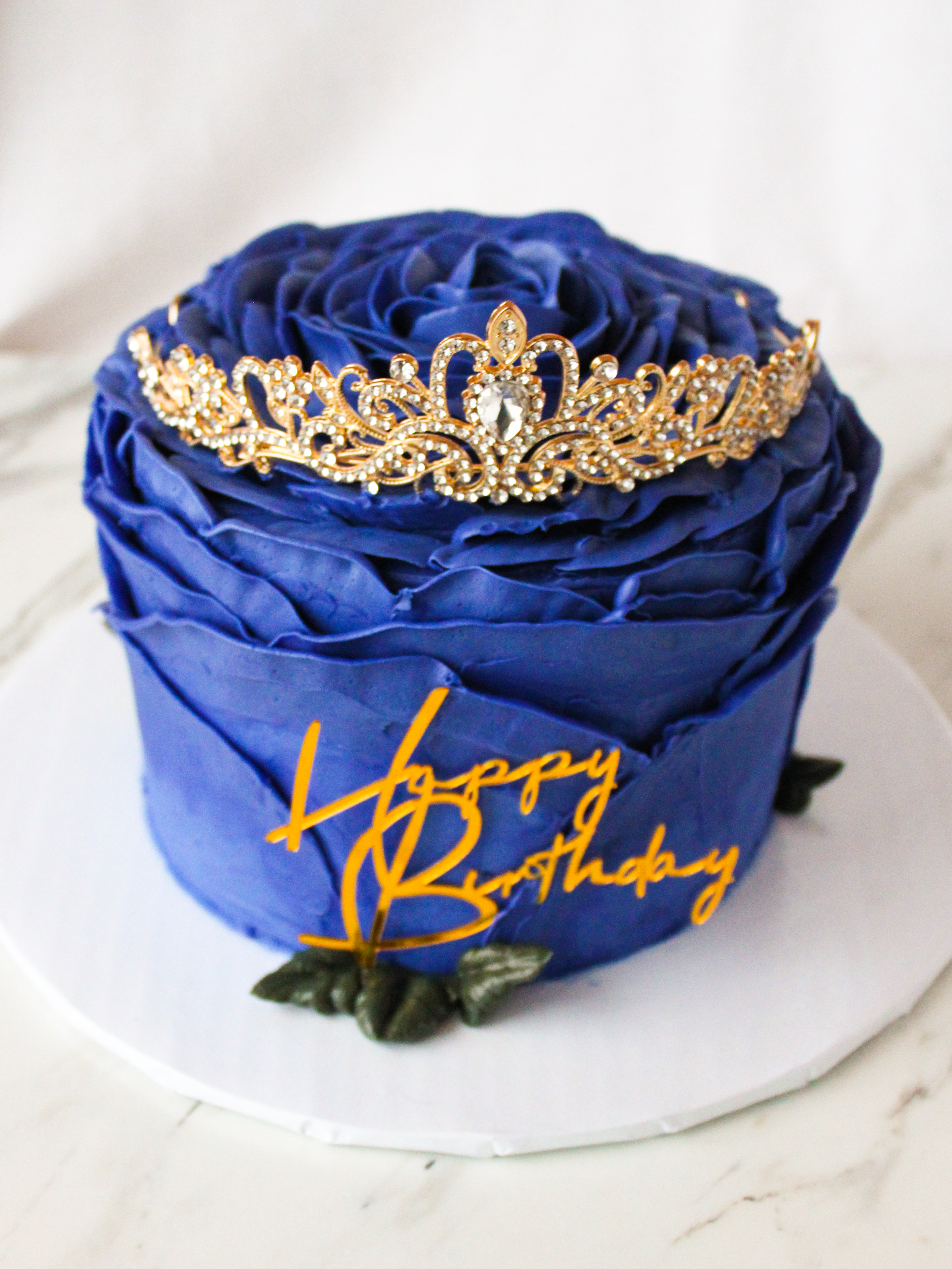 large single buttercream rose cake adorned with tiara and acrylic happy birthday cake charm