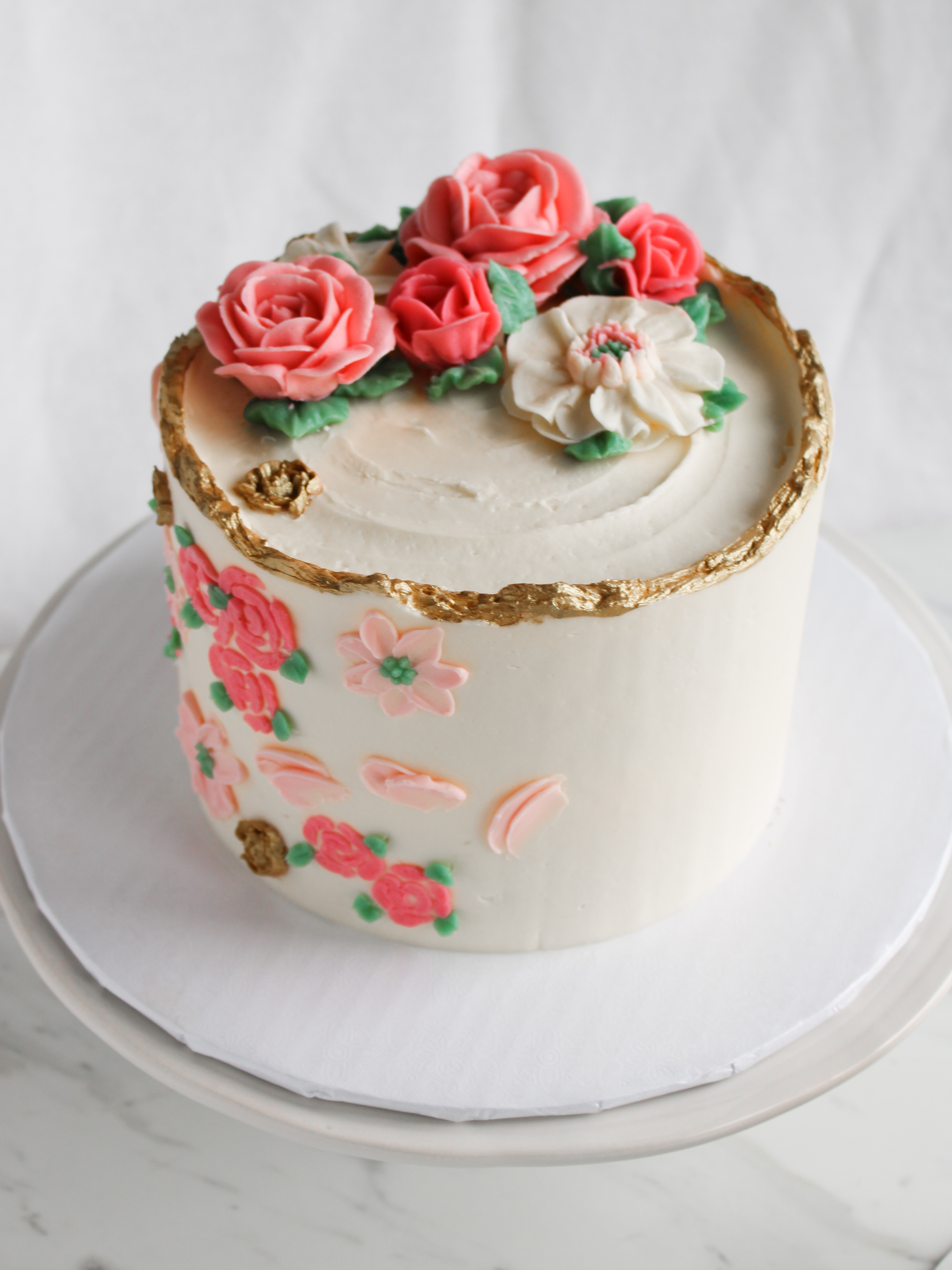 buttercream rose cake with gilt edges and palette knife flowers on side